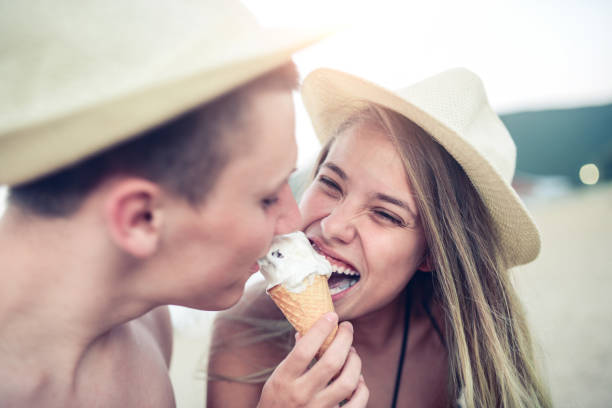 istock Young Smiling Couple how Biting One Ice Cream at Summer Beach 832301904