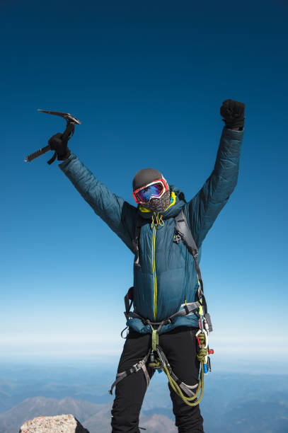 profesjonalny przewodnik hiker na szczycie skały z rękami do góry jest zadowolony z kolejnego zwycięstwa wznoszenia - on top of mountain peak success cold zdjęcia i obrazy z banku zdjęć