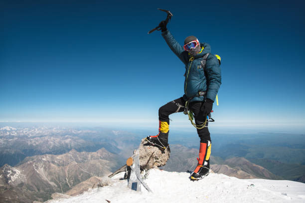 profesjonalny przewodnik hiker na szczycie skały z rękami do góry jest zadowolony z kolejnego zwycięstwa wznoszenia - on top of mountain peak success cold zdjęcia i obrazy z banku zdjęć