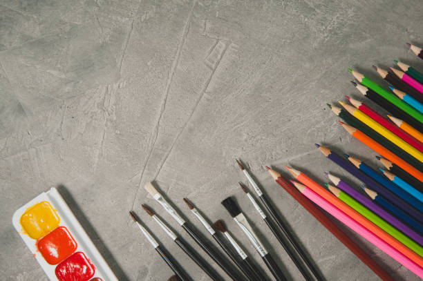 istock Drawing accessories - pencils, paints and brushes on a gray background 832389044