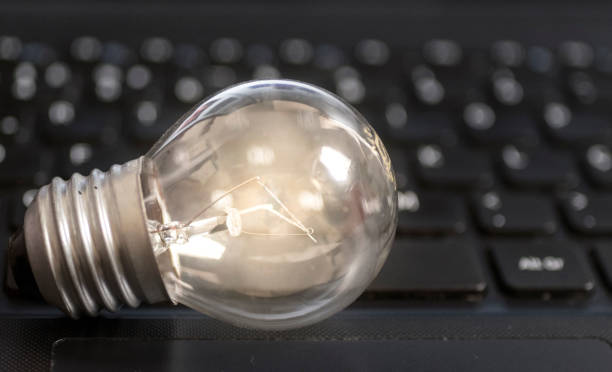 istock Lit light bulb lamp on top of a notebook computer black keyboard, technology concept and idea, with visible slightly out of focus keyboard letters. 832408186