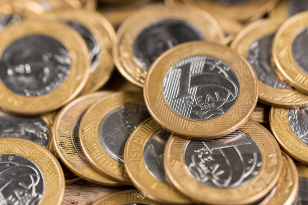 istock Several 1 real coins on a wooden table 832458970