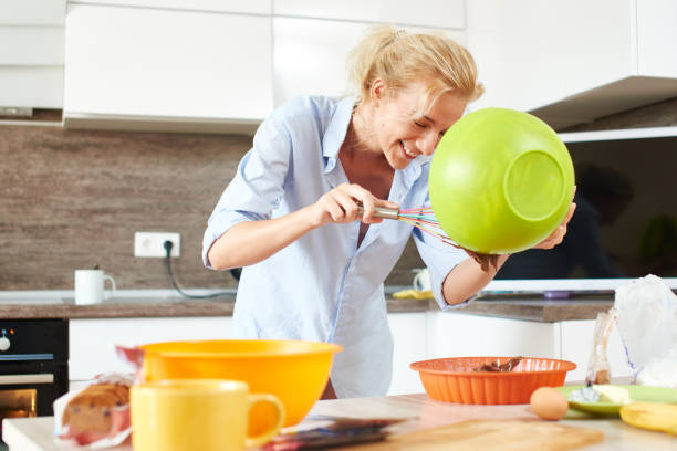 istock Young happy blond woman preparing dessert on white kitchen 832486156