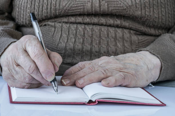 istock closeup wrinkled hands of a person writing 832509104