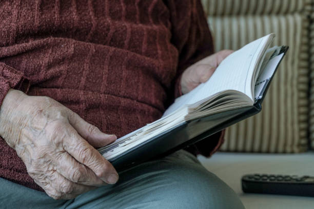 istock wrinkled hands of a person holding a book 832509124