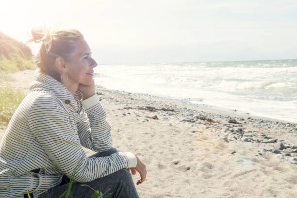 istock blond woman sitting on the beach 832514948