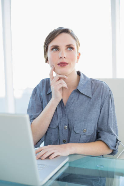 istock Thoughtful businesswoman using her notebook while sitting at her desk 832524968