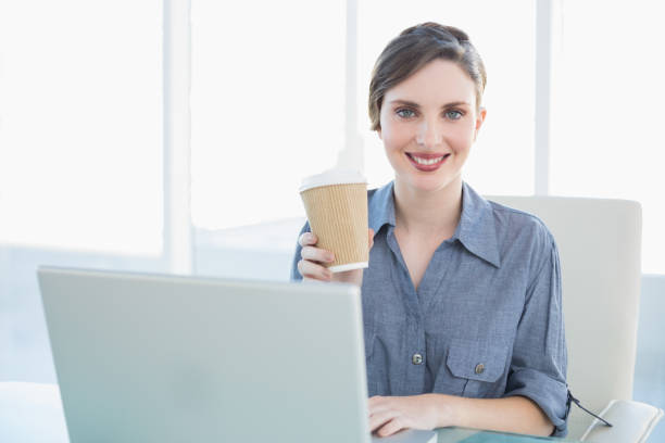 istock Calm beautiful businesswoman showing disposable cup while sitting at her desk 832525152