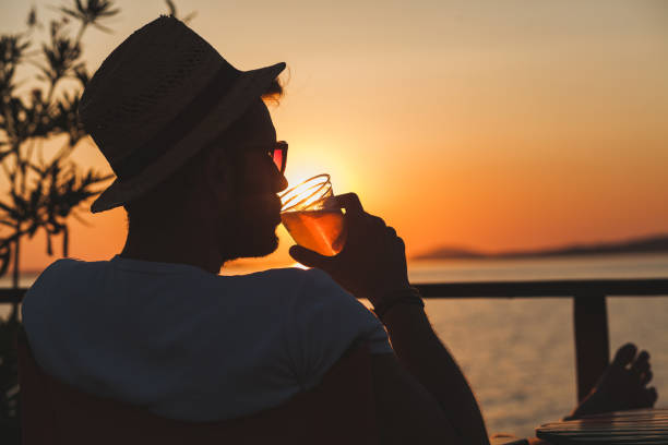 istock Young man enjoying sunset at a beach bar 832525794