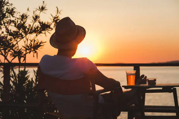 Photo of Young man enjoying sunset at a beach bar