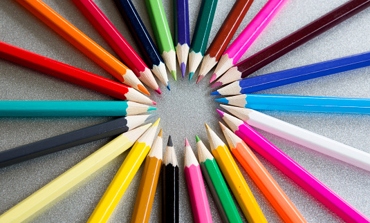 closeup of colored pencils in a circle on grey background