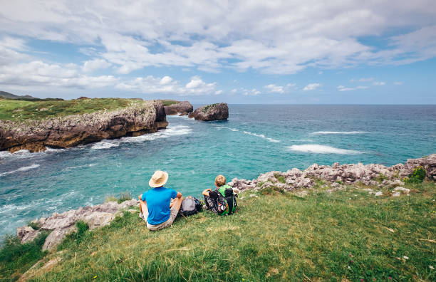 istock Father and son sitting on the rocky seaside 832560734