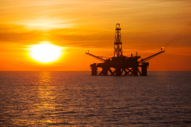 offshore installation in the middle of the ocean at sunset time - derrick crane drilling rig well sky imagens e fotografias de stock