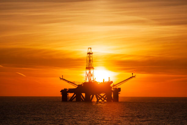instalação offshore no meio do oceano, ao tempo do sol - oil pumping unit at sunset time - fotografias e filmes do acervo