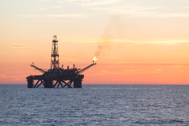 instalação offshore no meio do oceano, ao tempo do sol - oil pumping unit at sunset time - fotografias e filmes do acervo