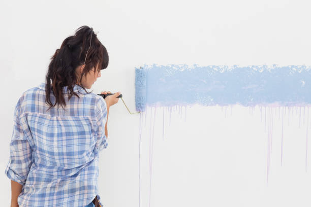 istock Woman painting wall blue 832659678