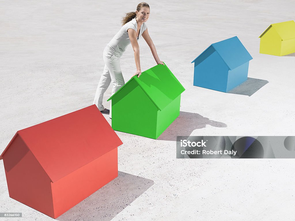 Donna in piedi con piccole case modello - Foto stock royalty-free di 25-29 anni