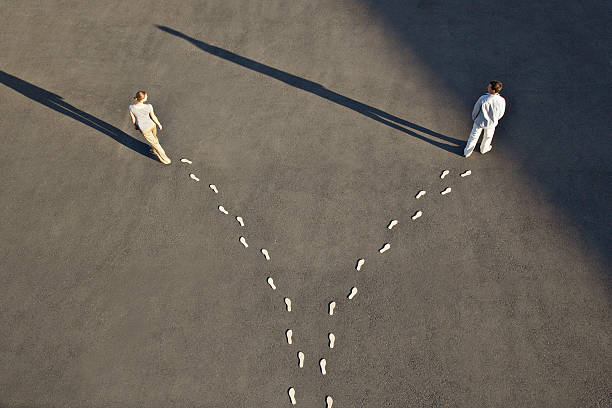 homem e mulher com divergente linha de footprints - fork in the road imagens e fotografias de stock