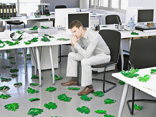 hombre de negocios en la oficina moderna rodeado de hojas - leaning forward fotografías e imágenes de stock