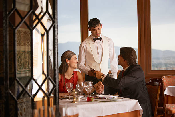 cameriere che serve coppia in elegante ristorante - servizio di lusso foto e immagini stock