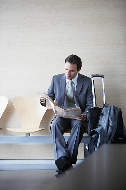 Businessman with suitcase reading newspaper  newspaper airport reading business person stock pictures, royalty-free photos & images