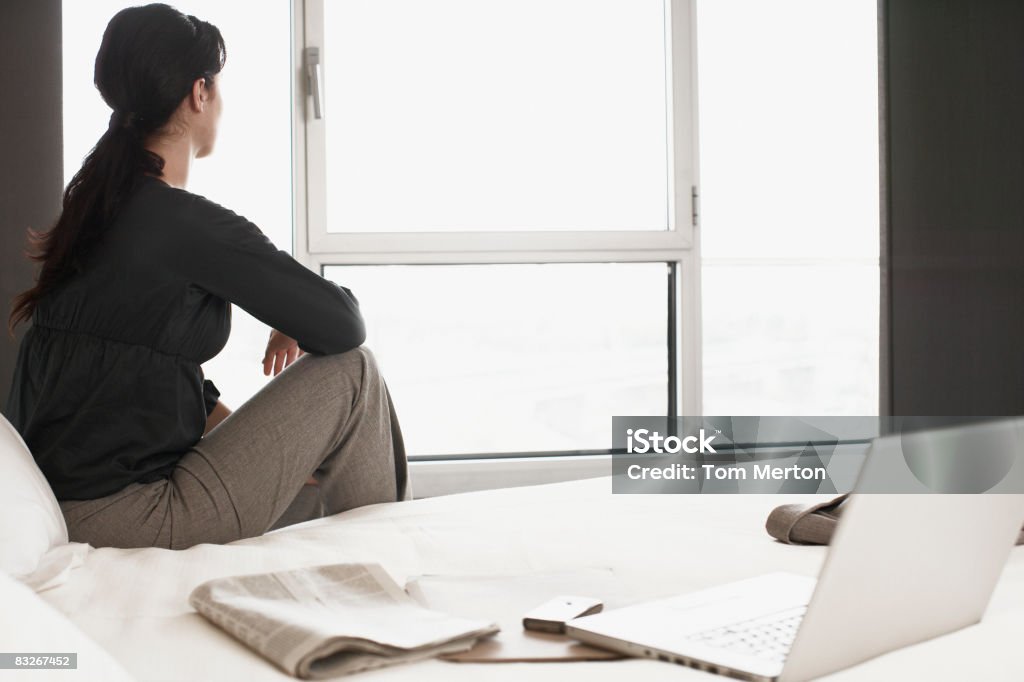 Businesswoman sitting on bed in hotel room  20-24 Years Stock Photo