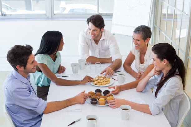 istock Business people chat while eating muffins and drinking coffee 832819728