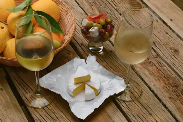 White wine, cheese, olives, fruits on table.
