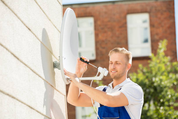 Man Installing TV Satellite Dish Smiling Young Man Installing TV Satellite Dish To Wall cable tv stock pictures, royalty-free photos & images