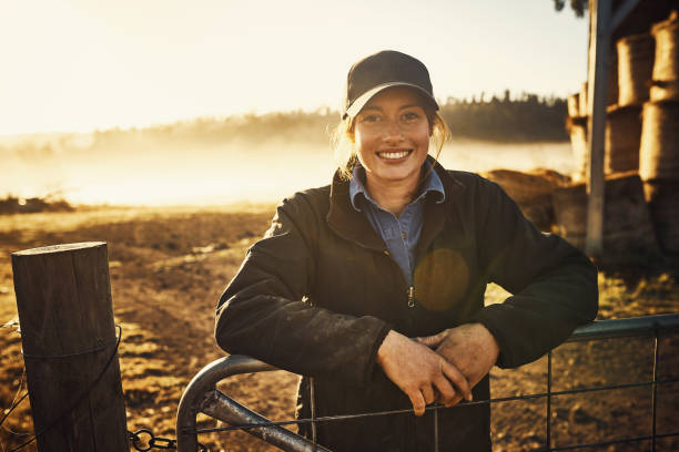 Living with nature right on my doorstep Portrait of a young woman leaning against a gate on a farm farmer stock pictures, royalty-free photos & images