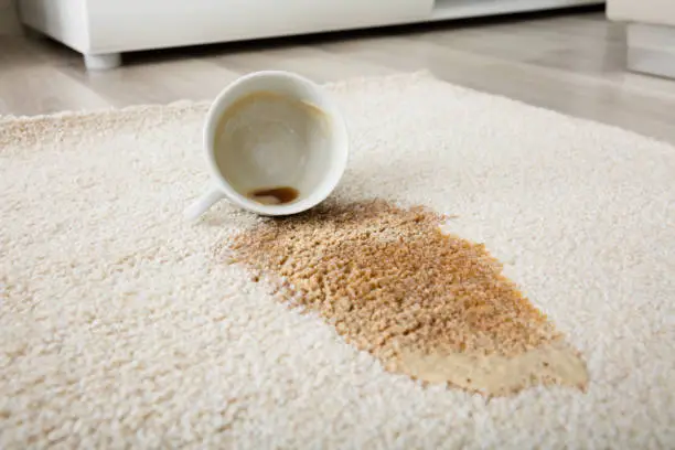 Close-up Of Coffee Spilling From Cup On Carpet