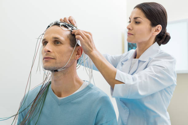 Female doctor putting electrodes on patients head Carefully and gently. Pleasant young female doctor fixing electrodes on the head of her patient while preparing him for the electroencephalography procedure x ray image medical occupation technician nurse stock pictures, royalty-free photos & images