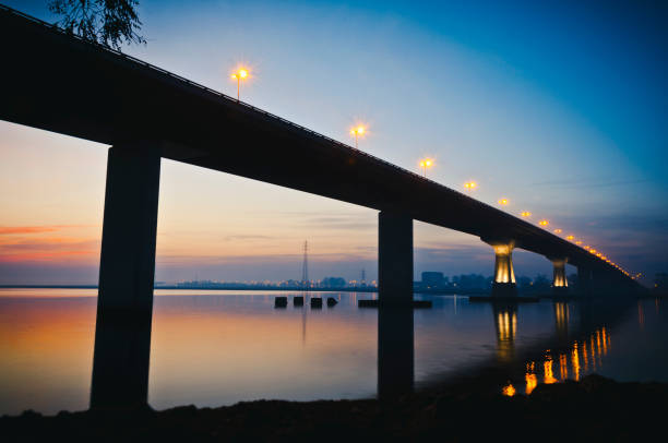 A large concrete bridge is seen against the light in the last hours of the day.