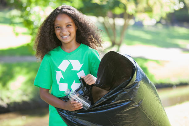 Young environmental activist smiling at the camera picking up trash Young environmental activist smiling at the camera picking up trash on a sunny day littering stock pictures, royalty-free photos & images