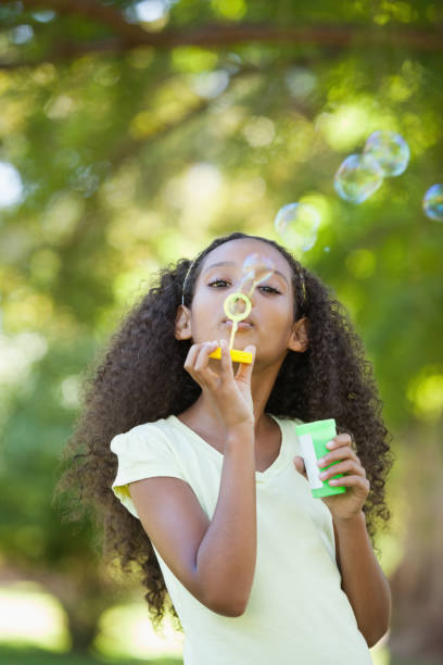 istock Young girl blowing bubbles in the park 833040782