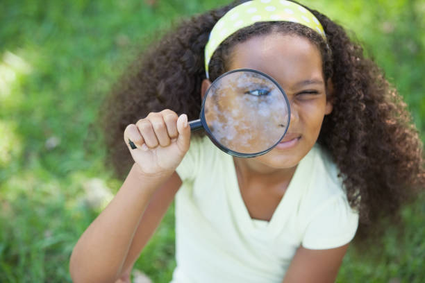 istock Young girl looking through magnifying glass in the park 833040856