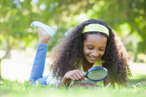 istock Young girl looking at grass through magnifying glass in the park 833040964