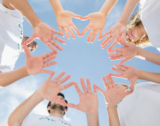 istock Volunteers with hands together against blue sky 833041440