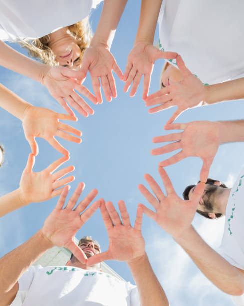 istock Volunteers with hands together against blue sky 833041496