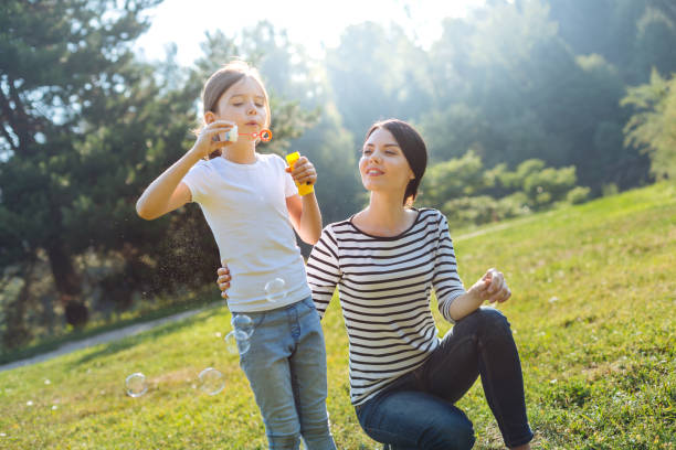 istock Loving mother watching her daughter play with soap bubbles 833070118