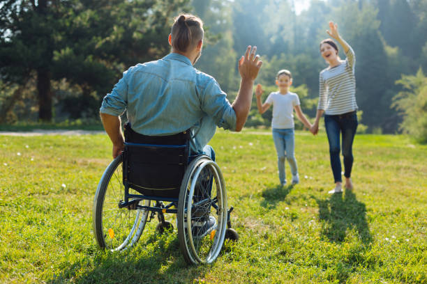 istock Young man with disabilities waving hello to his family 833076026