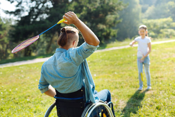 istock Mobility-impaired man passing shuttlecock to daughter 833083478