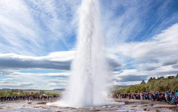 Strokkur geyser, Iceland A crowd is watching an eruption of the Strokkur geyser; clouds seemingly create an aura around the blast of the geyser golden circle route photos stock pictures, royalty-free photos & images