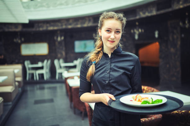 Waiters carrying plates with food, in a restaurant. Waiters carrying plates with meat dish at a wedding. waitress stock pictures, royalty-free photos & images