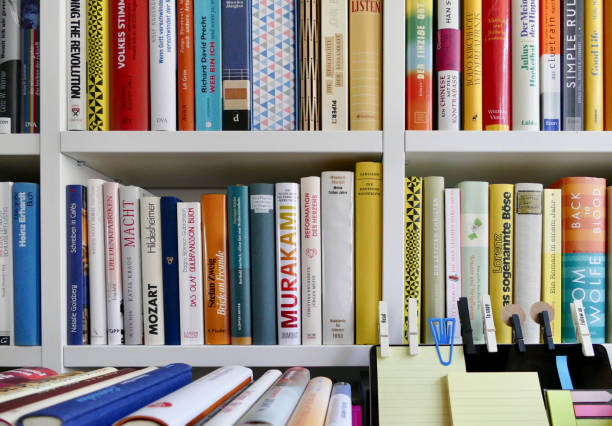 本の棚の前で粘着メモとカラフルなノート パソコン - book book spine shelf in a row ストックフォトと画像
