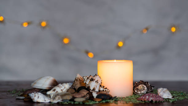 Table arrangement of three glass vases with sea shells and floating candles.