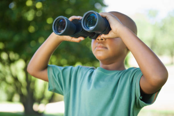 istock Little boy looking up through binoculars in the park 833145394