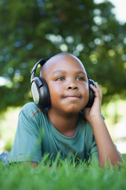 istock Little boy lying on grass listening to music 833147628