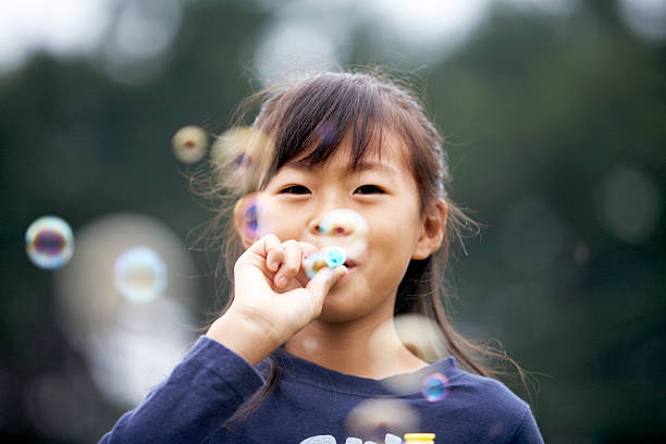 日本の女の子吹く泡 - bubble wand child blowing asian ethnicity ストックフォトと画像