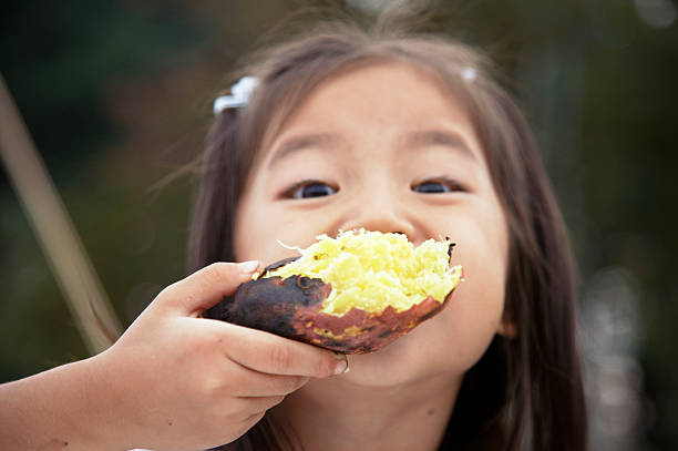 menina japonesa comer batata doce - young potatoes imagens e fotografias de stock